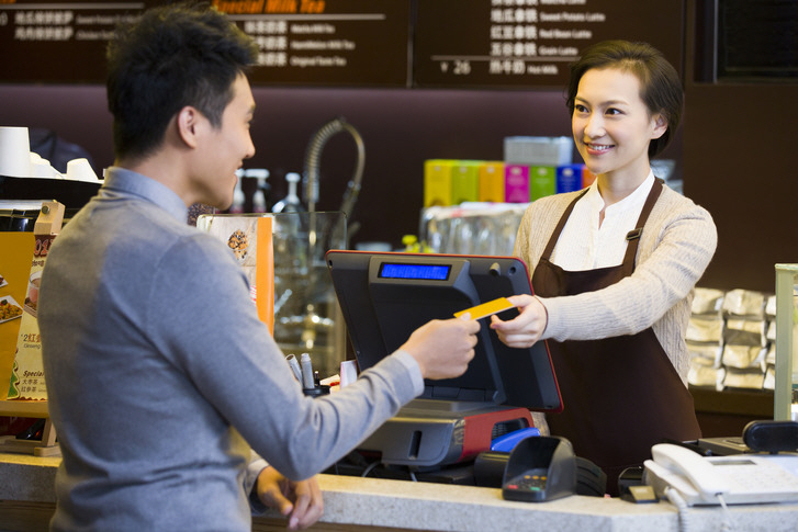 Customer paying by credit card in coffee shop